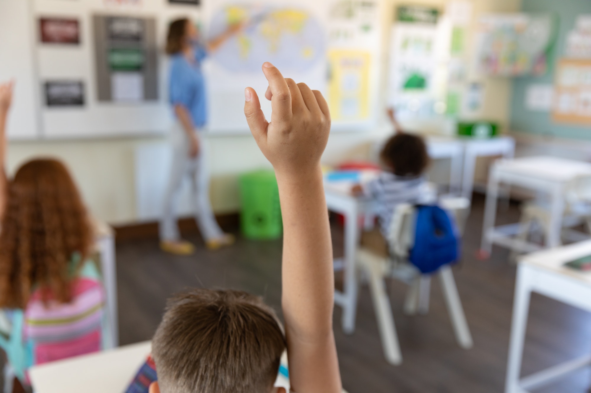 Students raising hands in class at school
